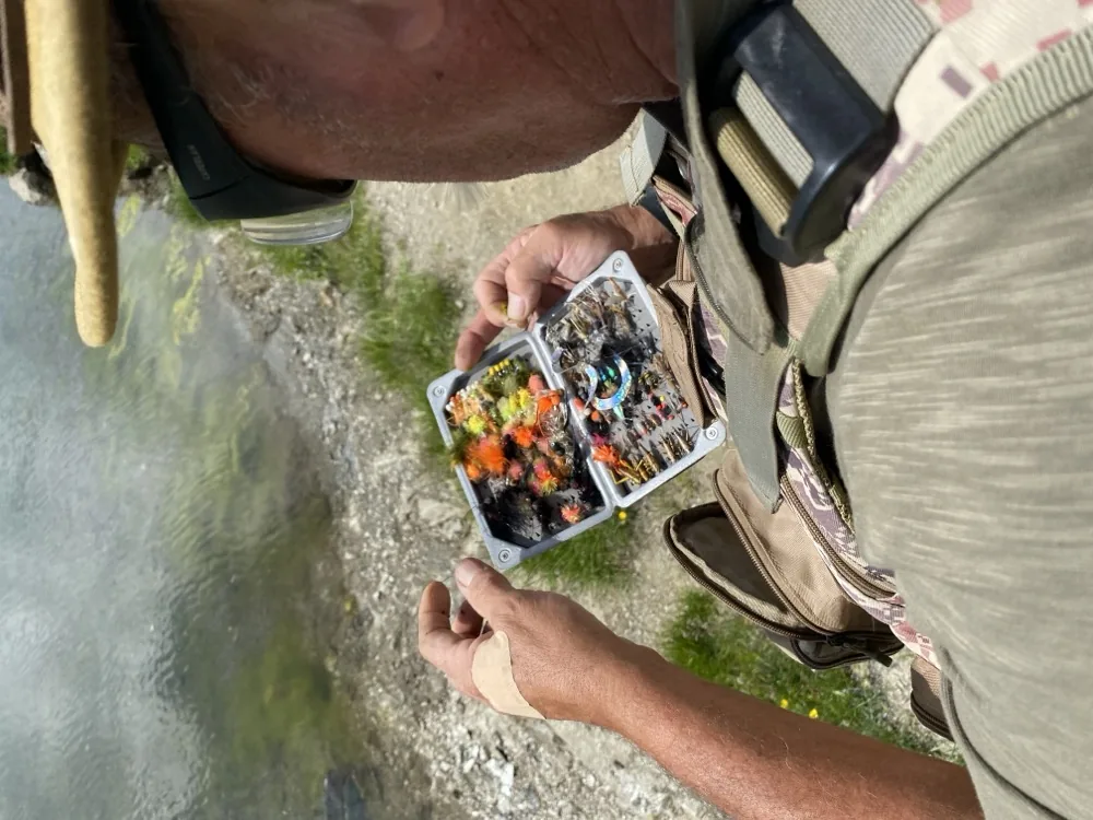 Pêcheur ouvrant sa boîte de mouches au bord du lac