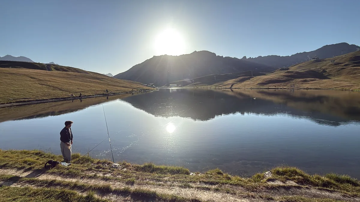 Pêcheur en contre-jour au bord du lac au soleil couchant